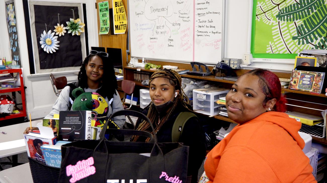 Three girls pose for a photo in class